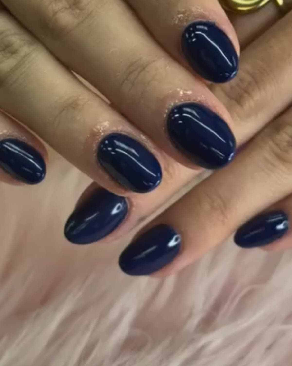 Uñas ovaladas cortas en azul noche con la cutícula perfilada en purpurina