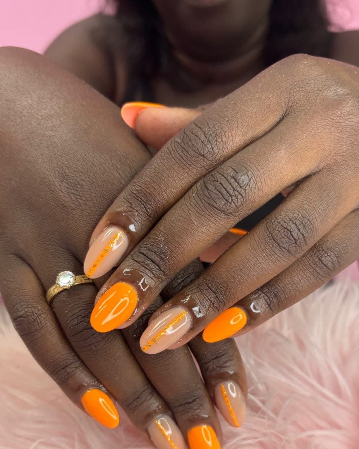 Manicura almendrada combinando naranja neón y nude con una línea de cristales dorados